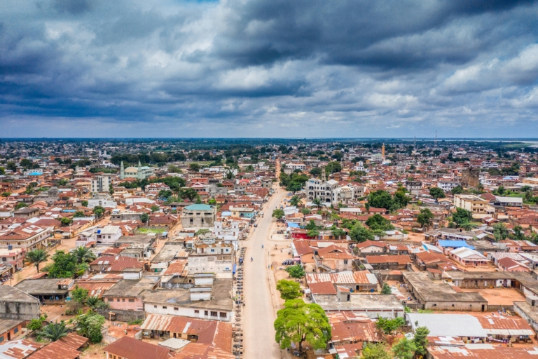Vue aérienne d'une ville africaine avec des toits en tôle rouge sous un ciel nuageux.